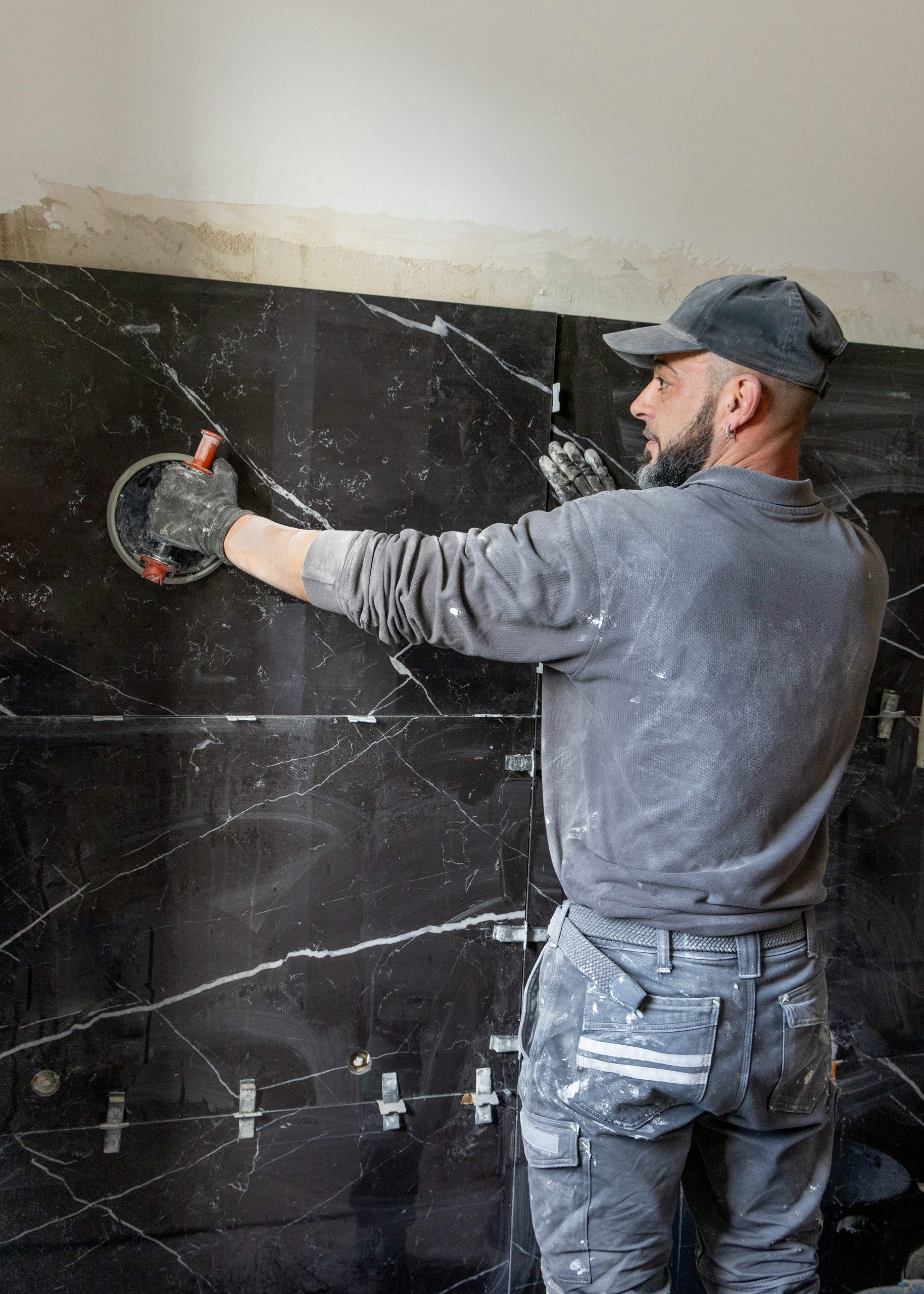 man-applying-large-tile-on-a-bathroom-wall-using-s-2026-01-11-11-04-52-utc